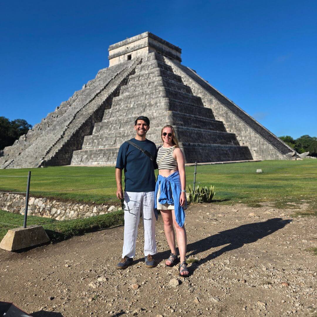 Pareja de viajeros frente al Templo de Kukulkán en Chichén Itzá, Yucatán